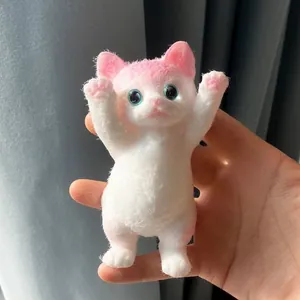 Vue détaillée d'un jouet antistress chat mignon peint à la main blanc et rose tenu en main