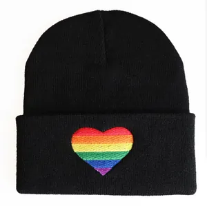 Close-up of black knitted beanie featuring a vibrant rainbow heart embroidery on the cuff