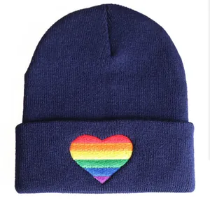Detailed macro view of vibrant rainbow heart embroidery on a navy blue knitted beanie