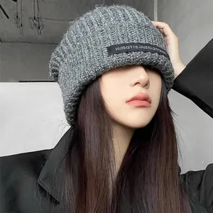 Close-up view of a stylish grey chunky knit beanie with a black branded label detail.
