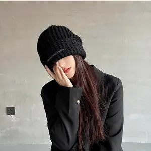 Detailed view of a trendy black knitted beanie featuring a unique casual fabric patch.