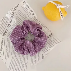 Gros plan d'un chouchou à carreaux violets sur papier vintage avec un citron décoratif