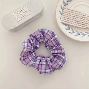 Gros plan d'un chouchou en tissu à carreaux violets sur un fond de table esthétique
