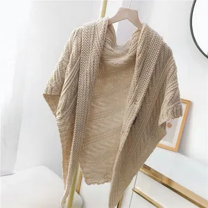 Detailansicht eines eleganten cremefarbenen Strickponchos mit aufwendigem Zopfmuster