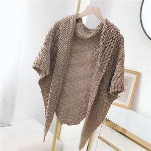 Detailansicht eines beigen Strick-Ponchos mit Wellenmuster-Textur.