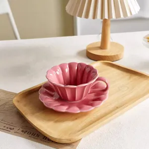 Elegantes Set aus rosa Keramik-Kaffeetasse und Untertasse mit Blumenfalten für Zuhause