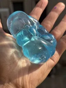 Close-up detail of a translucent blue maltose squishy stress relief toy held in sunlight