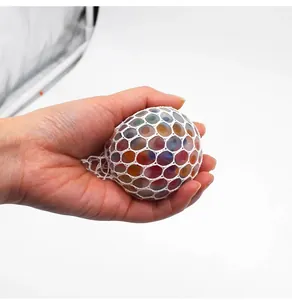 Hand drückt einen bunten Perlen-Netz-Stressball zur Entspannung