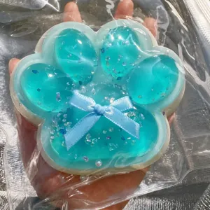 Μάκρο προβολή μπλε διαφανούς squishy πατούσα γάτας με γκλίτερ και φιόγκο