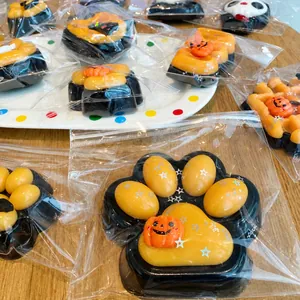 Detail shot of Halloween-themed cat paw squeeze toys with pumpkin designs in packaging