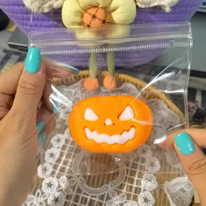 Close-up detail of an orange Halloween pumpkin squeeze squishy toy inside a clear plastic bag