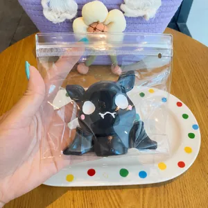 Soft black bat Halloween squeeze toy held in hand inside clear zip bag packaging