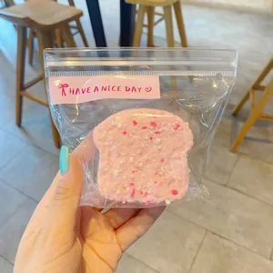 Detailed macro view of a pink toast-shaped squishy stress relief toy in a clear bag