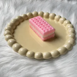 Close-up view of a pink soda cracker sandwich squishy toy on a beige decorative plate