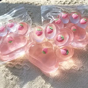 Close-up detail of a soft pink cat paw squishy toy featuring tiny strawberry inclusions inside