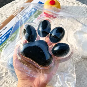 Detailed close-up of oversized black cat paw squishy toy for stress relief in a clear bag