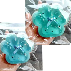 Detail view of teal translucent cat paw squishy toy with glitter in clear packaging