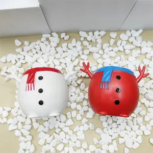 Gros plan détaillé des jouets à presser bonhomme de neige de Noël sur des galets blancs.
