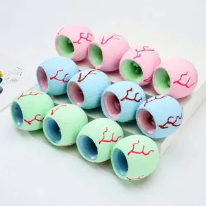 Close-up of colorful dinosaur eye squeeze toys showing pink, blue, and green color options