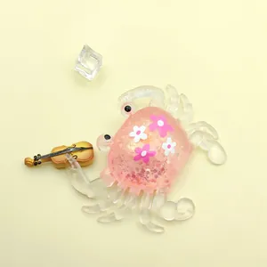 Close-up detail of a pink crab squeeze toy filled with glitter holding a mini violin