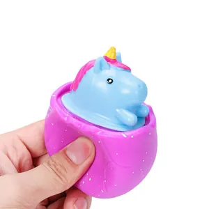Blue unicorn stress relief squeeze toy popping out of a purple egg shaped cup toy for kids
