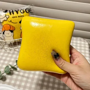 Close-up of butter yellow toast squishy toy being squeezed for slow rising stress relief