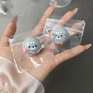 Close-up detail of two cute gray seal squishy toys with lollipop and cutlery in clear bags.