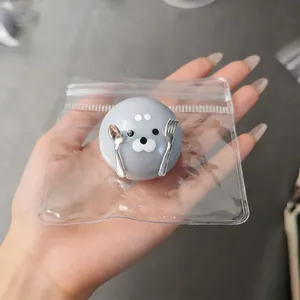 Detailed view of a cute gray seal squishy toy with mini spoon and fork accessory in hand