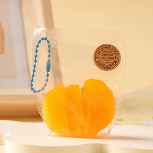 Gros plan d'un jouet à presser orange dans son sachet avec une petite chaîne bleue