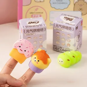 Primer plano de mini juguetes blandos de panadería en los dedos con embalaje de caja ciega.