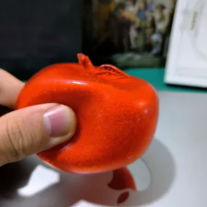 Hand squeezing red slushy apple squishy toy to show elastic texture