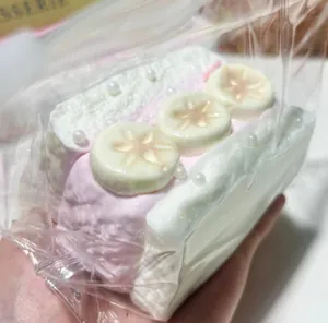 Detailansicht eines realistischen Squishy-Toastkuchens mit Sahnetextur und Bananenscheiben.