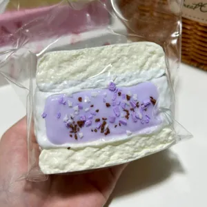 Detailansicht eines Toast-Squishy-Spielzeugs mit lila Creme und Streuseln in Verpackung