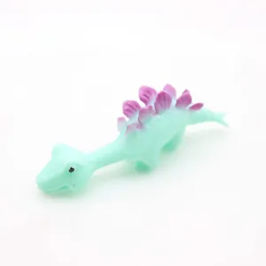 Detailed macro shot of a soft mint green Stegosaurus slingshot toy with purple plates