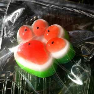 Macro view of watermelon-colored cat paw squishy stress relief toy in clear packaging