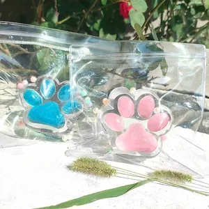Close-up of pink and blue cat paw squishy toys in clear zip bags against a sunny garden