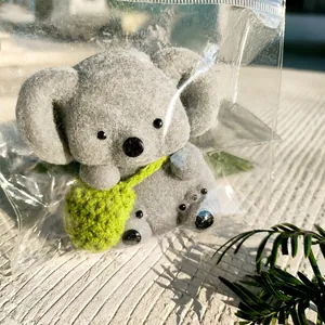 Gros plan d'un jouet spongieux koala gris avec un petit sac à dos tricoté en vert.