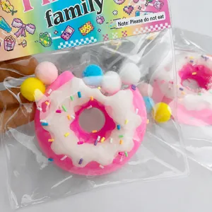 Rosa-weißer Donut-Squishy mit bunten Pompons in der Verpackung