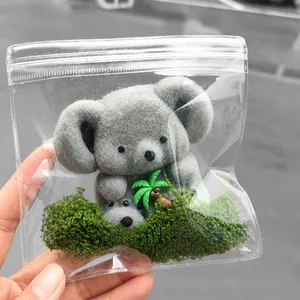 Gros plan d'un jouet anti-stress koala gris dans un sac avec mousse et palmier.
