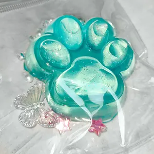 Close-up of a glittery turquoise cat paw squishy toy in plastic packaging