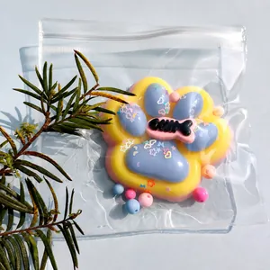 Detail view of a rainbow cat paw squishy stress relief toy with glitter and fish bone charm