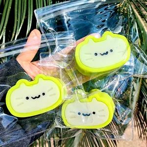 Close-up view of three green cheese cat squishy toys in clear packaging held by hand
