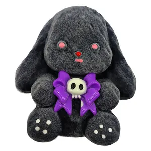 Dettaglio di un giocattolo squishy a forma di coniglio grigio scuro con fiocco viola e teschio