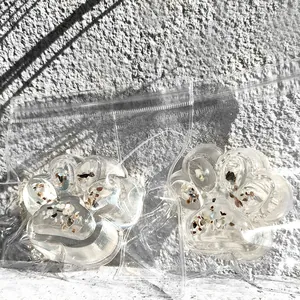 Close-up of two transparent cat paw squishy toys with colorful glitter inclusions.