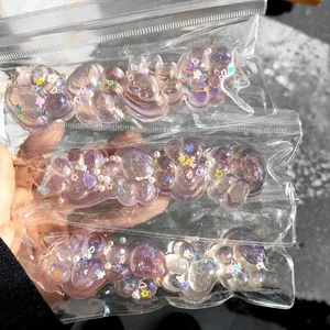 Detailansicht von lila glitzernden Katzenpfoten-Quetschspielzeugen in Klarsichtbeuteln