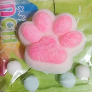 Close-up detail of a pink and white fuzzy cat paw squishy toy in retail packaging