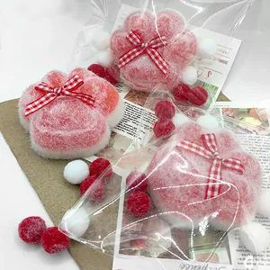 Close-up of three pink and white flocked cat paw squishies in cute decorative clear packaging