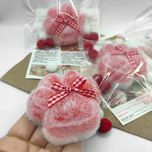 Close-up macro shot of a soft pink flocked cat paw squeeze toy featuring a cute red checkered bow