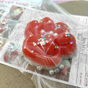 Cute red and white silicone cat paw squeeze toy with glitter stars and pearls detail view.