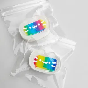 Macro view of two rainbow-colored cheese cat squishy toys in individual clear zipper bags.